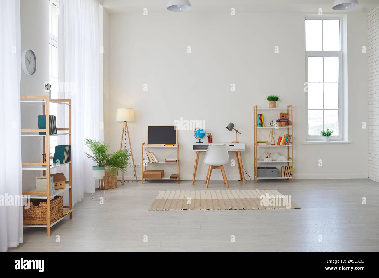Grande chambre d'enfants avec un bureau, étagères, tableau noir, plantes, livres, jouets et tapis Banque D'Images