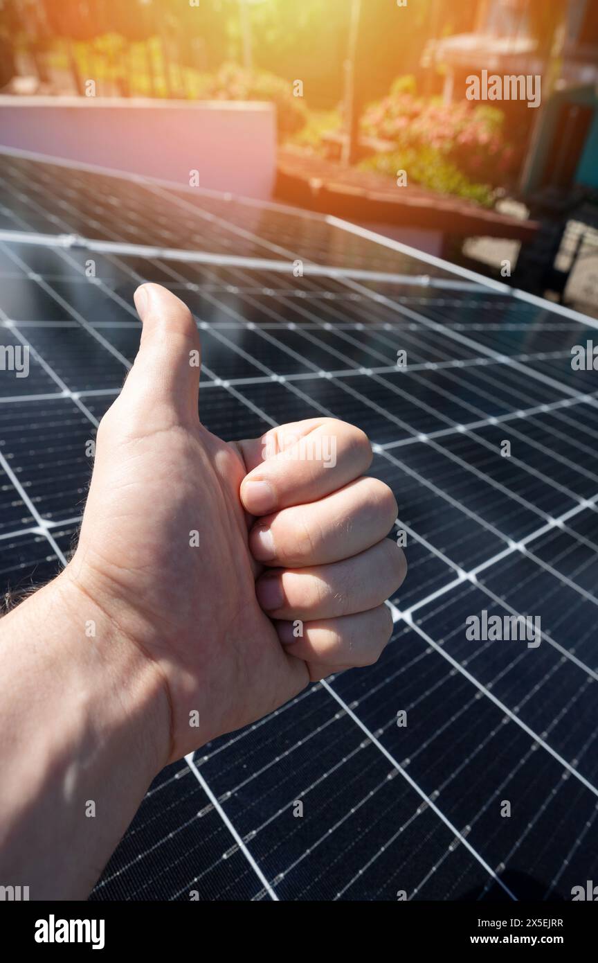 Vue rapprochée du pouce vers le haut sur l'arrière-plan du panneau solaire Banque D'Images