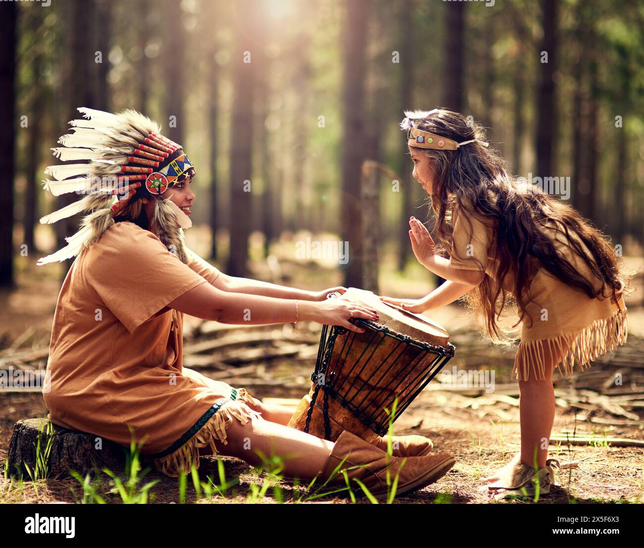 Chef amérindien, femme et tambour dans la nature avec enfant pour la musique, la connexion et l'apprentissage de l'histoire de la tribu. Instruments, mère et fille avec Banque D'Images