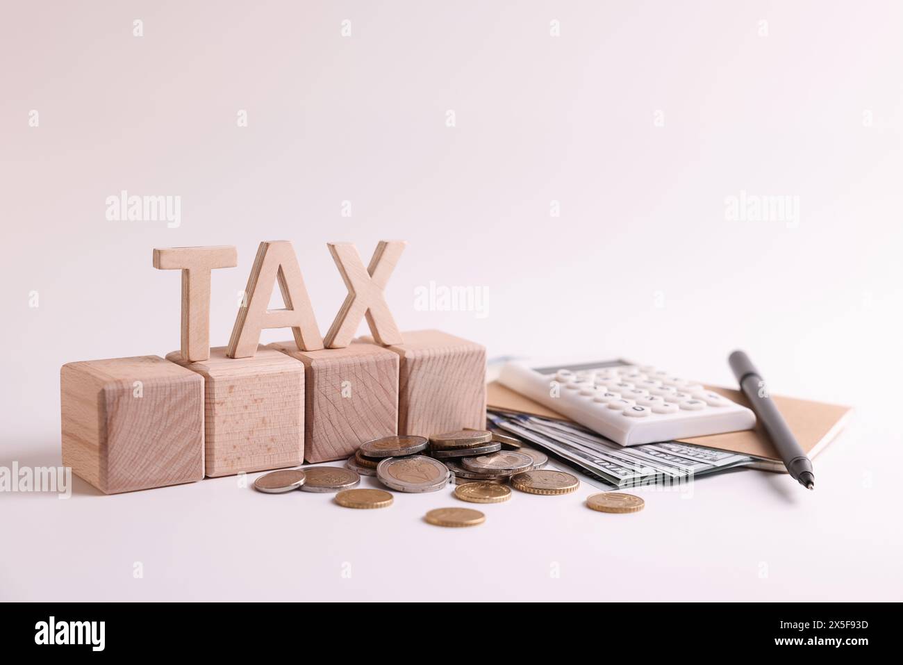 Word Tax, numéro 2024 fait de cubes en bois, calculatrice, pièces de monnaie et billets de banque sur fond blanc Banque D'Images