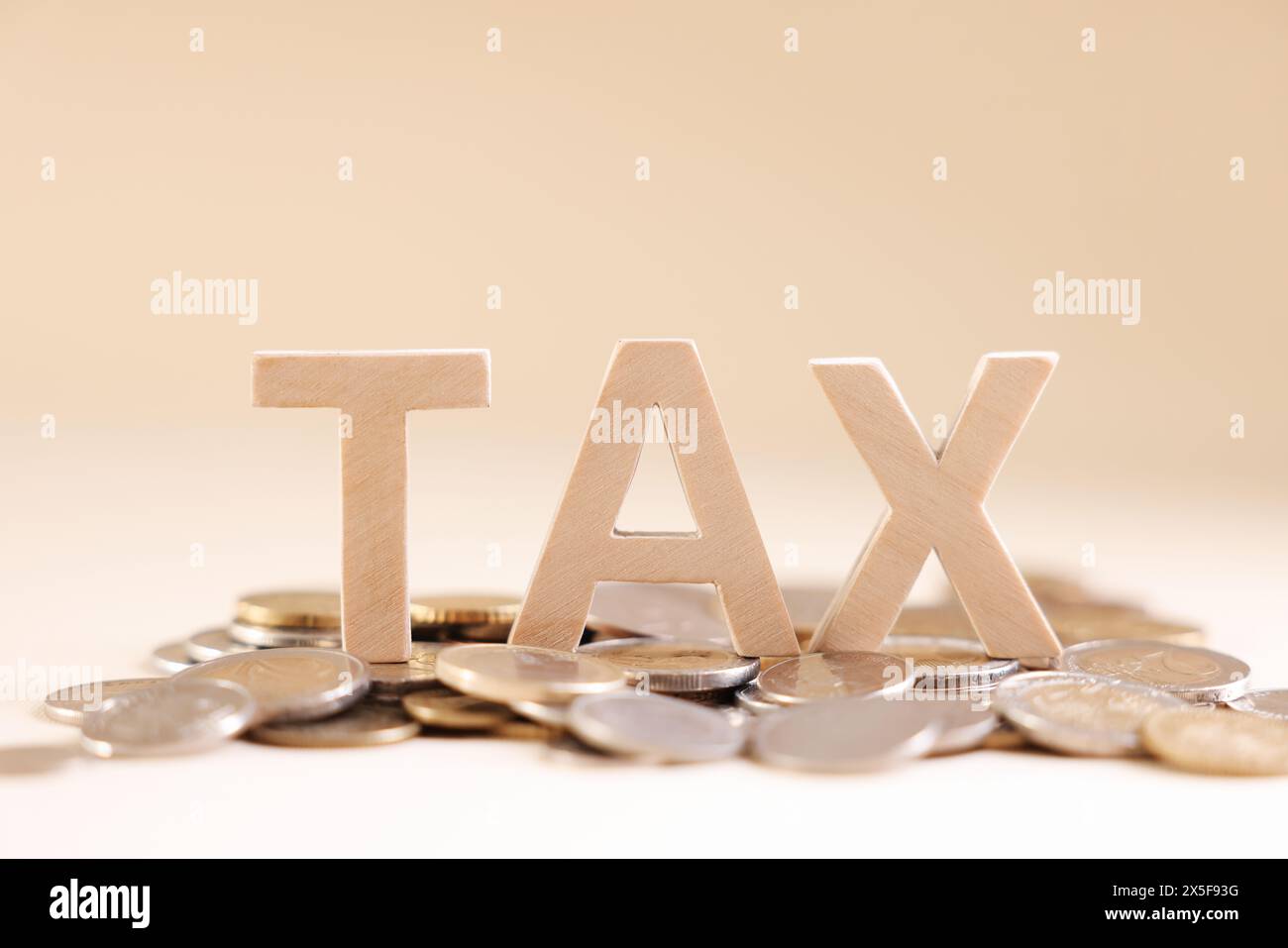 Mot Tax fait de lettres en bois et de pièces de monnaie sur fond beige Banque D'Images