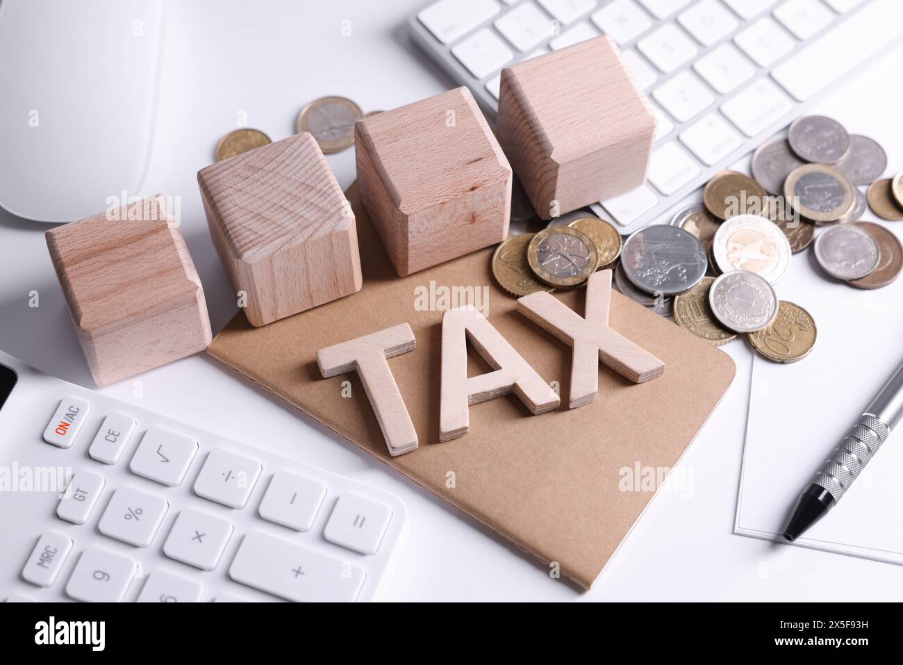 Word Tax, cubes en bois, calculatrice, pièces de monnaie, clavier et stylo sur table blanche Banque D'Images