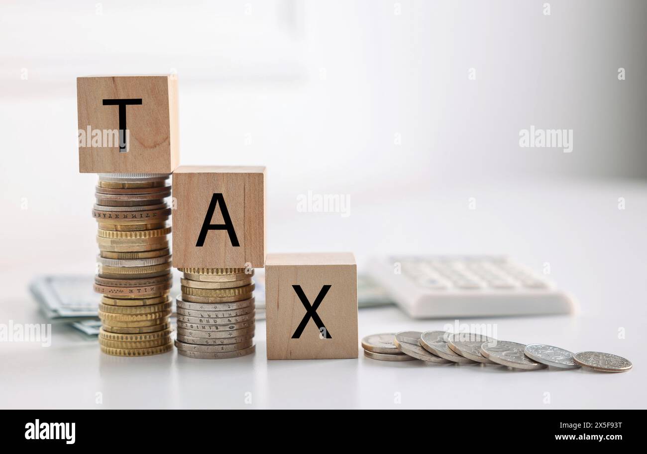 Word Tax fait de cubes en bois, pièces de monnaie et calculatrice sur table blanche Banque D'Images