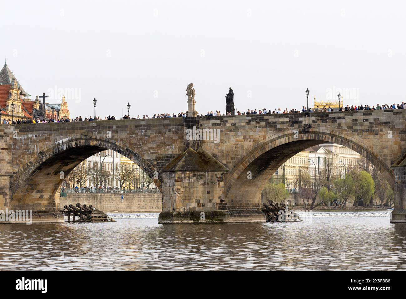 Prague, république tchèque - 3 mars 2024 : touristes marchant sur le pont Charles vu ci-dessous de la rivière Vltava Banque D'Images