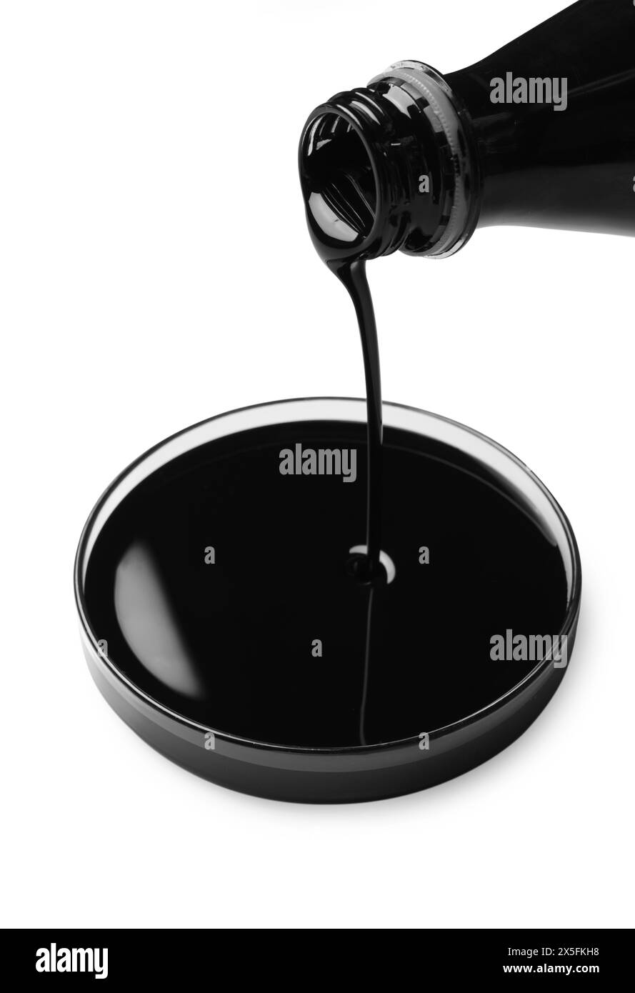 Verser du pétrole brut noir dans la boîte de Petri sur fond blanc Banque D'Images