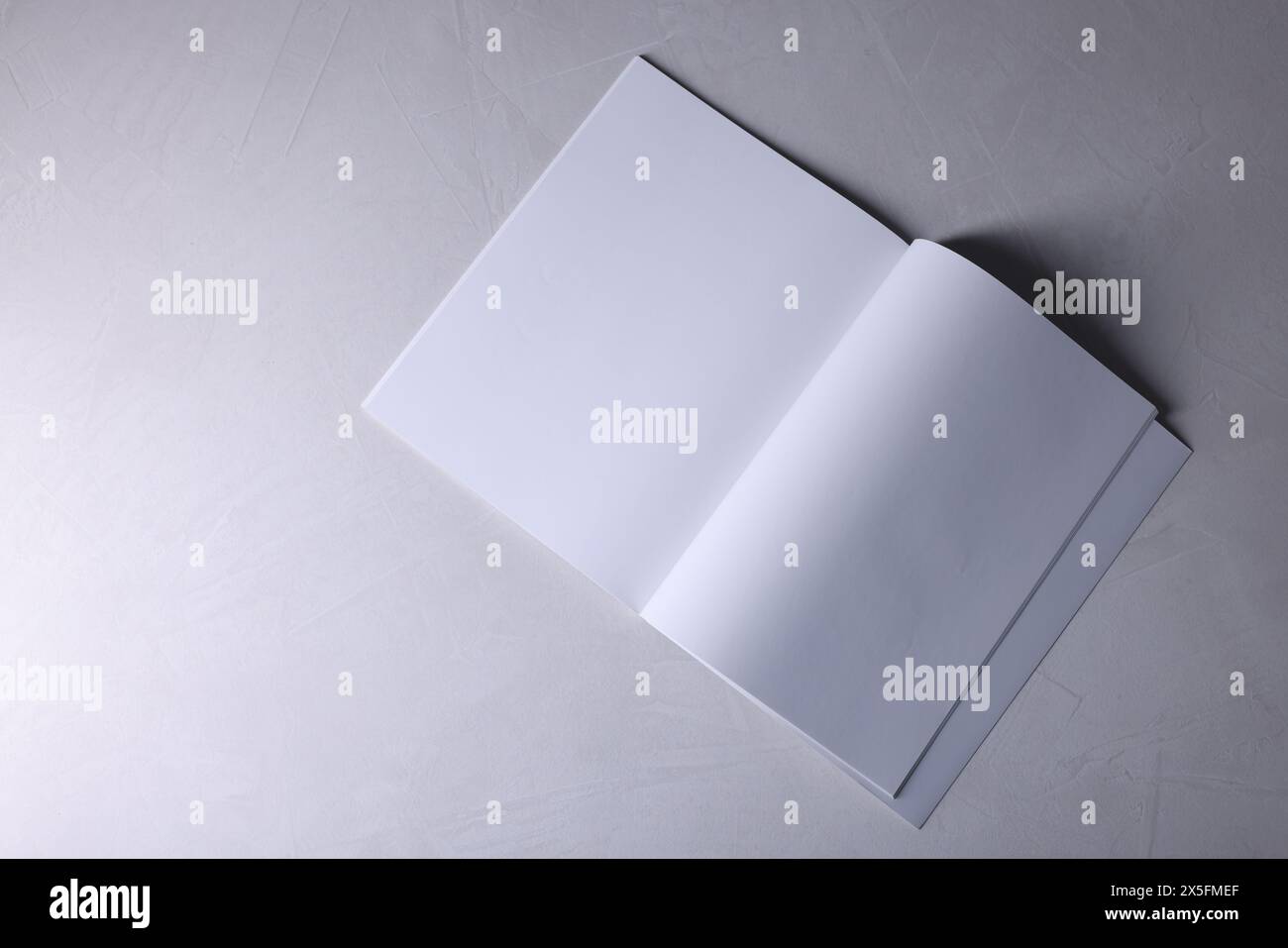 Ouvrez le carnet avec des feuilles de papier vierges sur fond texturé gris, vue de dessus. Maquette pour le design Banque D'Images