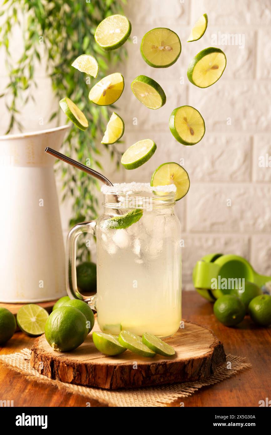Tranches de citrons frais tombant sur le verre avec de la limonade maison, verre avec de la paille en métal et décoré avec une tranche de citron. Banque D'Images