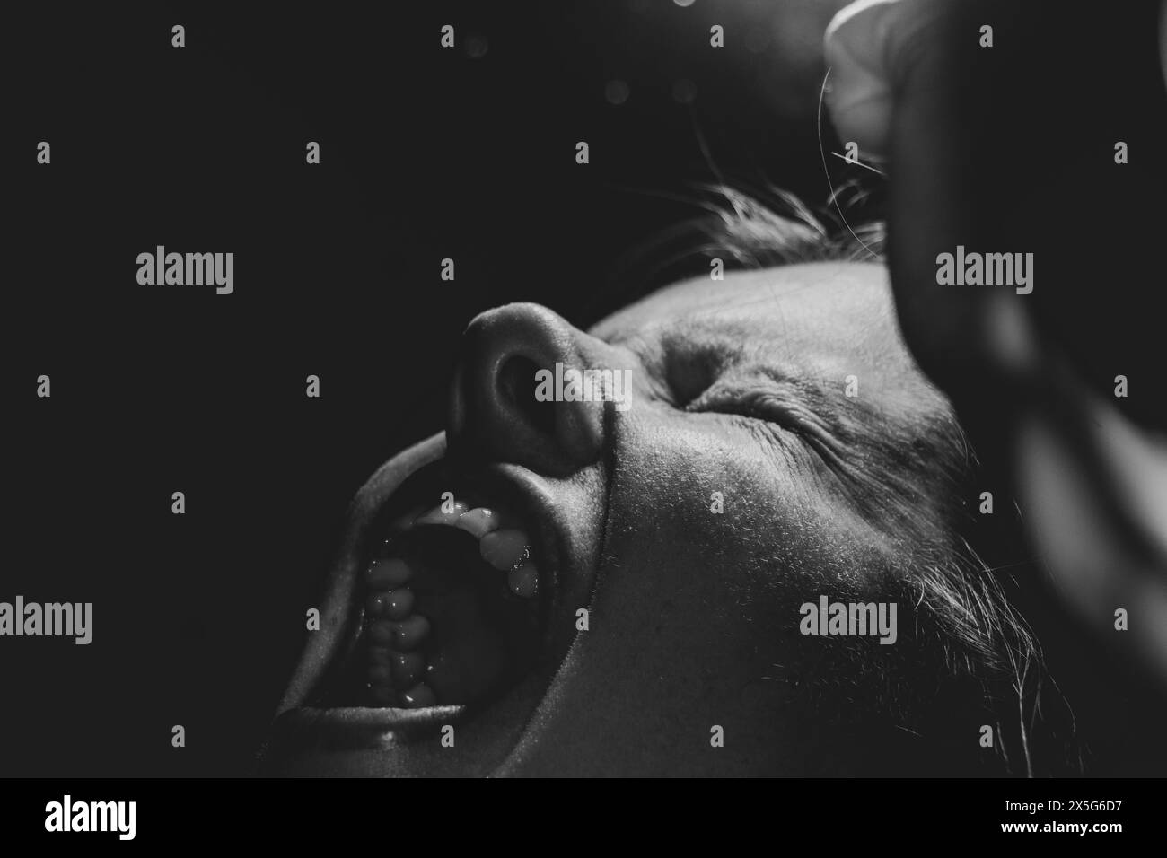 Une fille pleure et crie dans l'obscurité par la lumière d'une lanterne, une forte émotion négative et la rage, un cri de l'âme et la douleur Banque D'Images