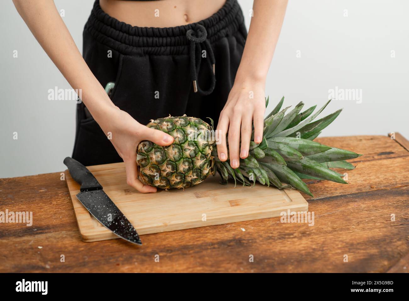 Ananas bio fermement tenu, prêt pour des recettes saines, sur bois. Banque D'Images