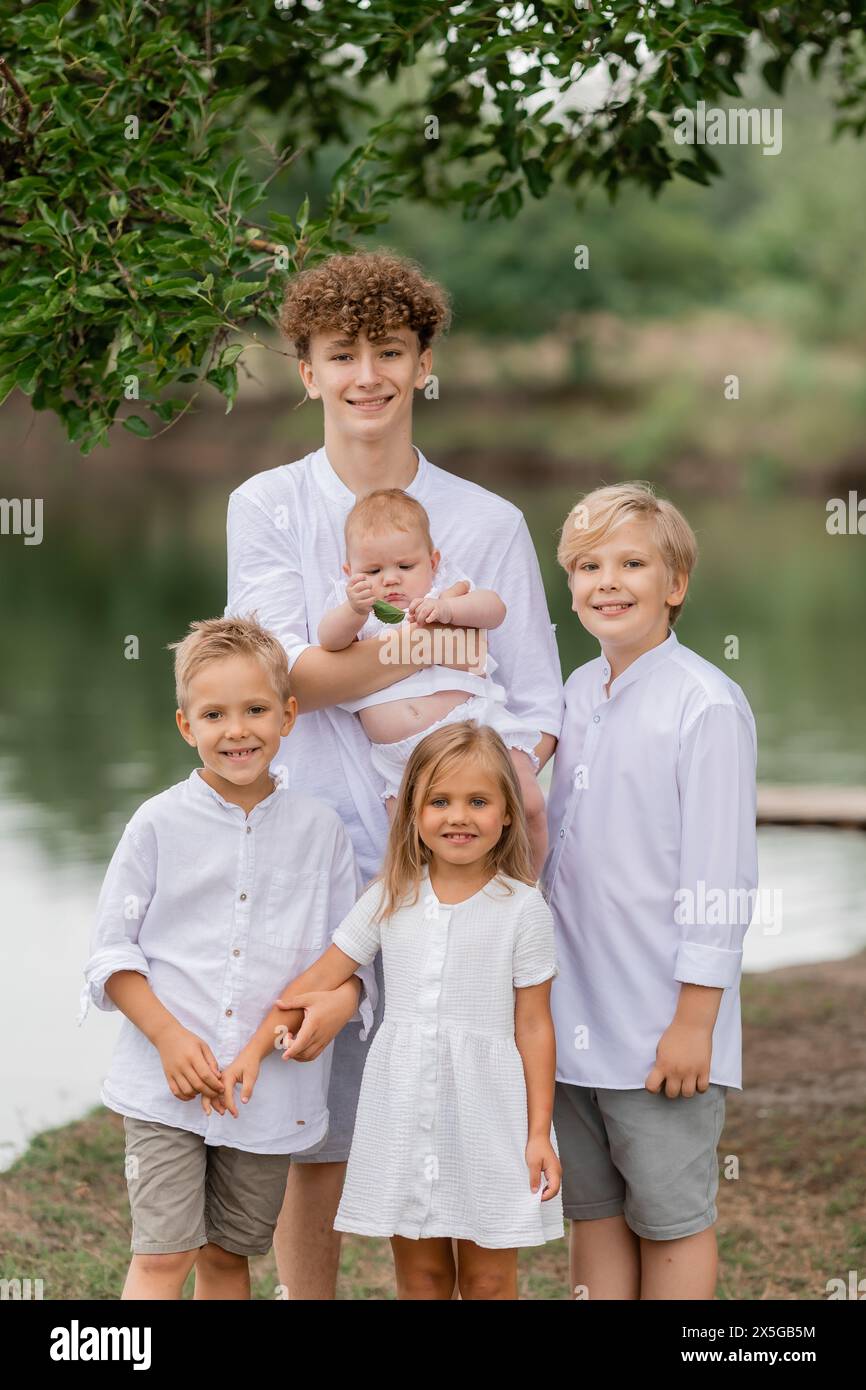 enfants, frères et sœurs marchent près du lac en été, une grande famille. Photo de haute qualité Banque D'Images