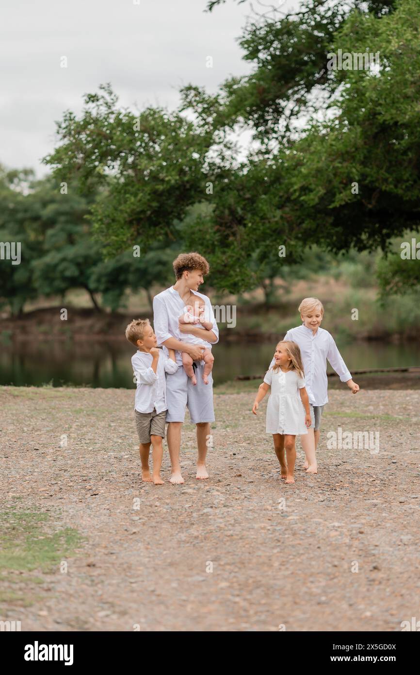 enfants, frères et sœurs marchent près du lac en été, une grande famille. Photo de haute qualité Banque D'Images