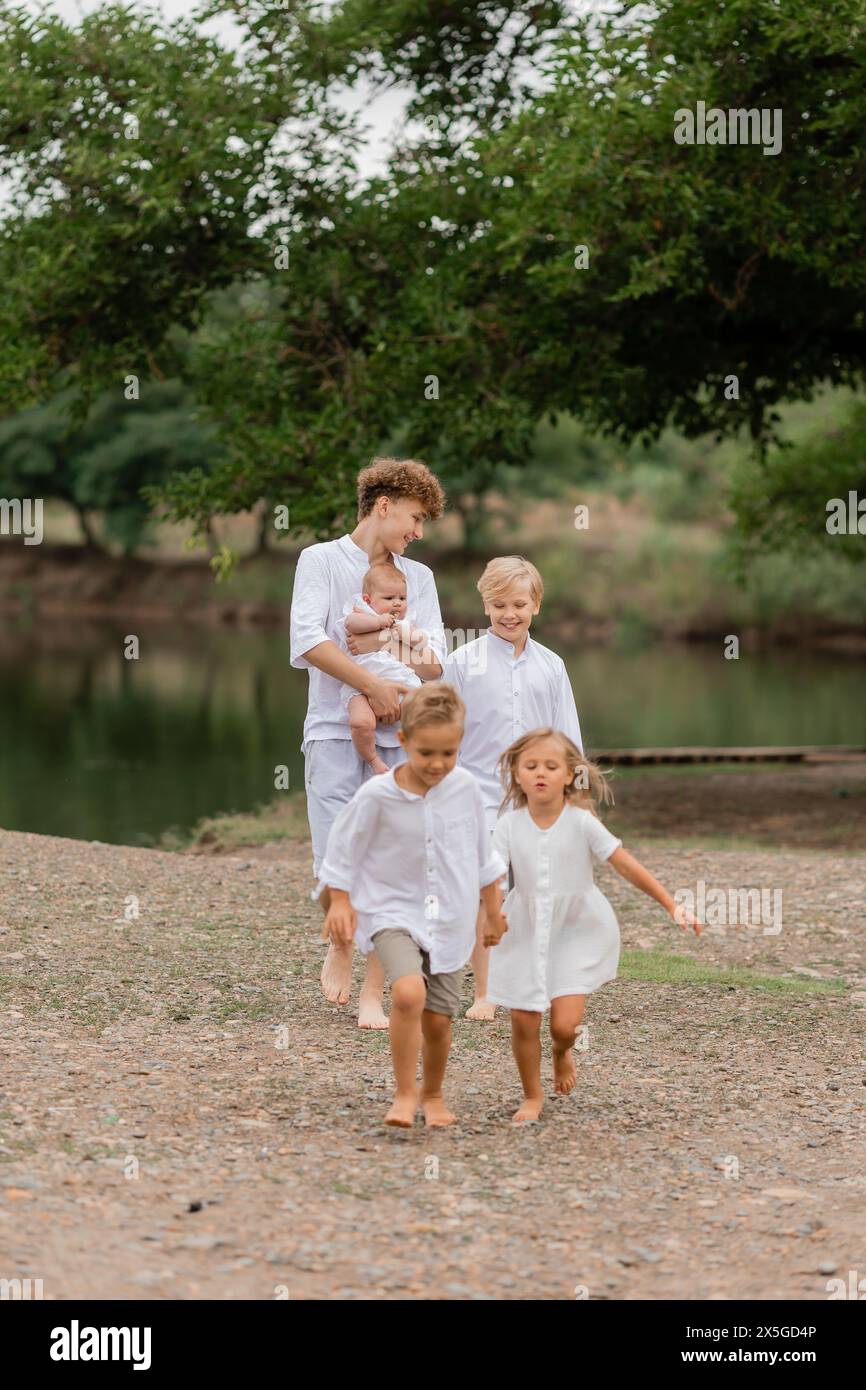 enfants, frères et sœurs marchent près du lac en été, une grande famille. Photo de haute qualité Banque D'Images