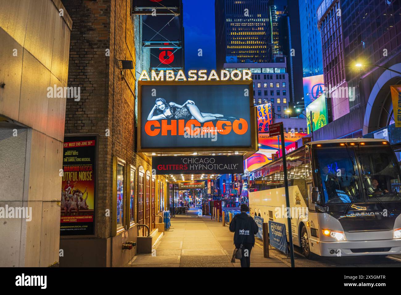 Scène nocturne animée de l'Ambassador Theater de Chicago avec des panneaux lumineux annonçant la comédie musicale « Chicago » et la vie urbaine animée. New York. Banque D'Images