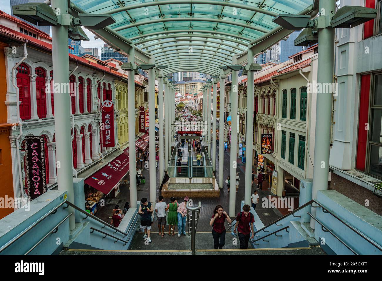 Cette image capture une arcade animée dans un cadre urbain, avec des façades colorées de style colonial sous un revêtement moderne, avec des piétons agréables Banque D'Images