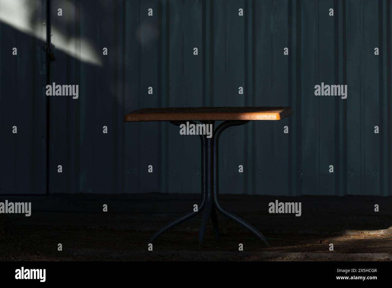 Interaction matinale. Table en bois ensoleillée dans une ambiance sombre. Lumière et ombre. Entre deux mondes. Banque D'Images