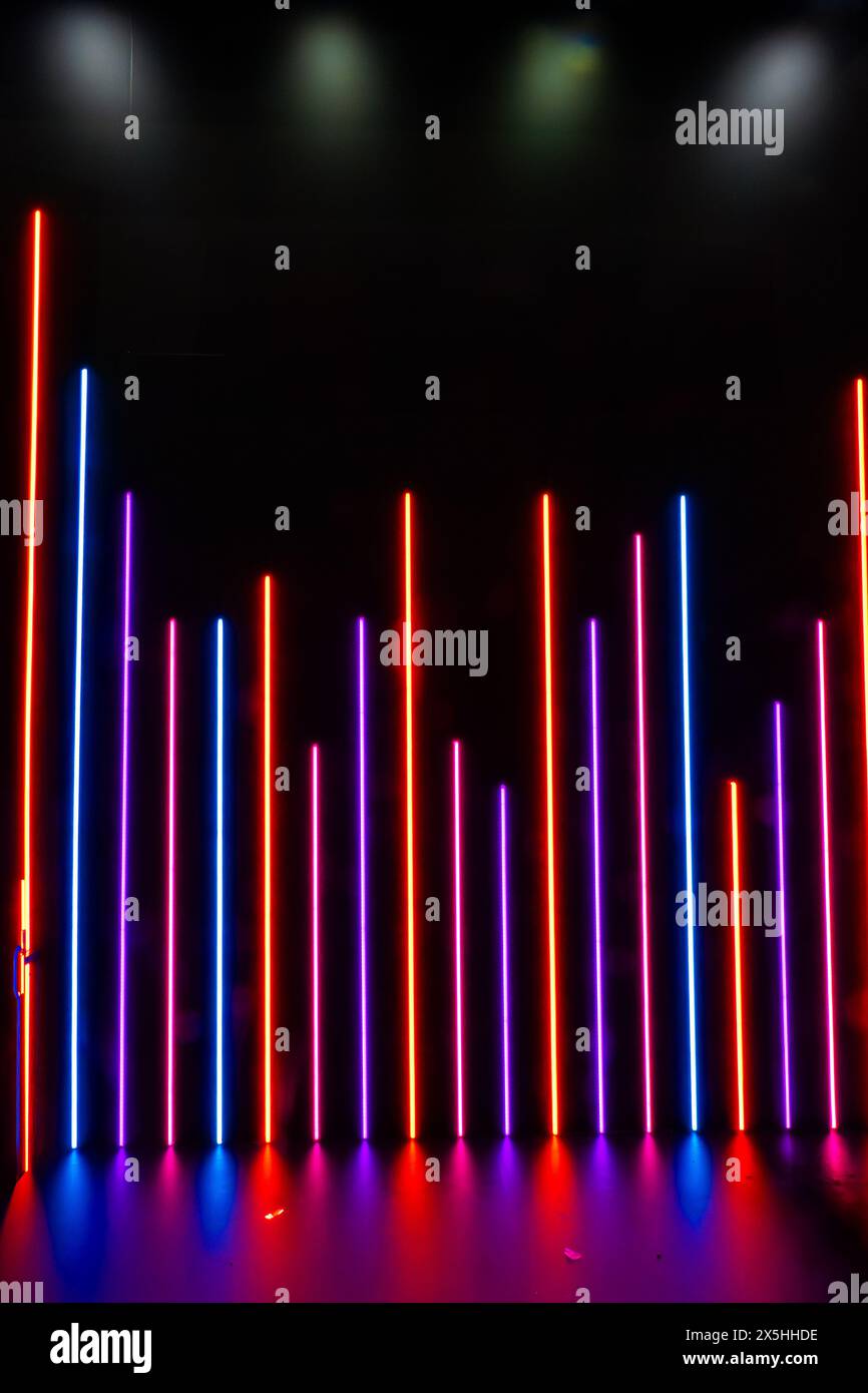 Lignes colorées de néons créant une scène visuellement vibrante. Les lampes sont disposées en rangée, chaque lampe étant située à une hauteur différente. Moderne Banque D'Images