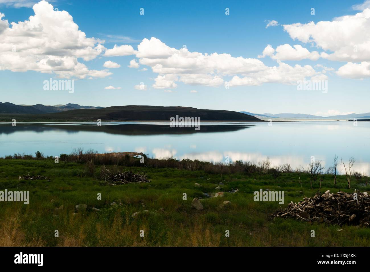 Paysage de lac paisible avec des eaux bleues réfléchissantes et le ciel. Banque D'Images