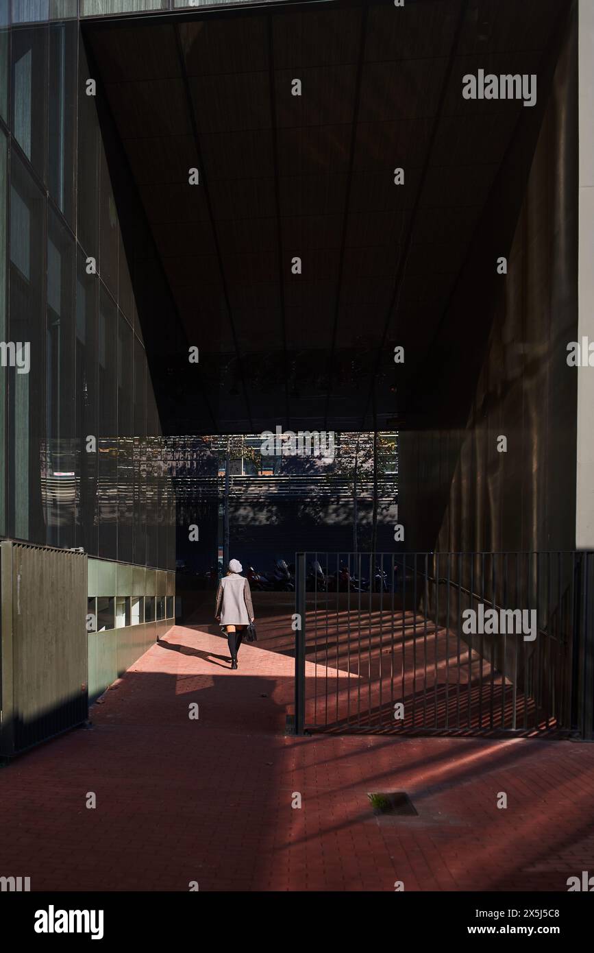 Figure solitaire marchant sous une structure urbaine géométrique Banque D'Images