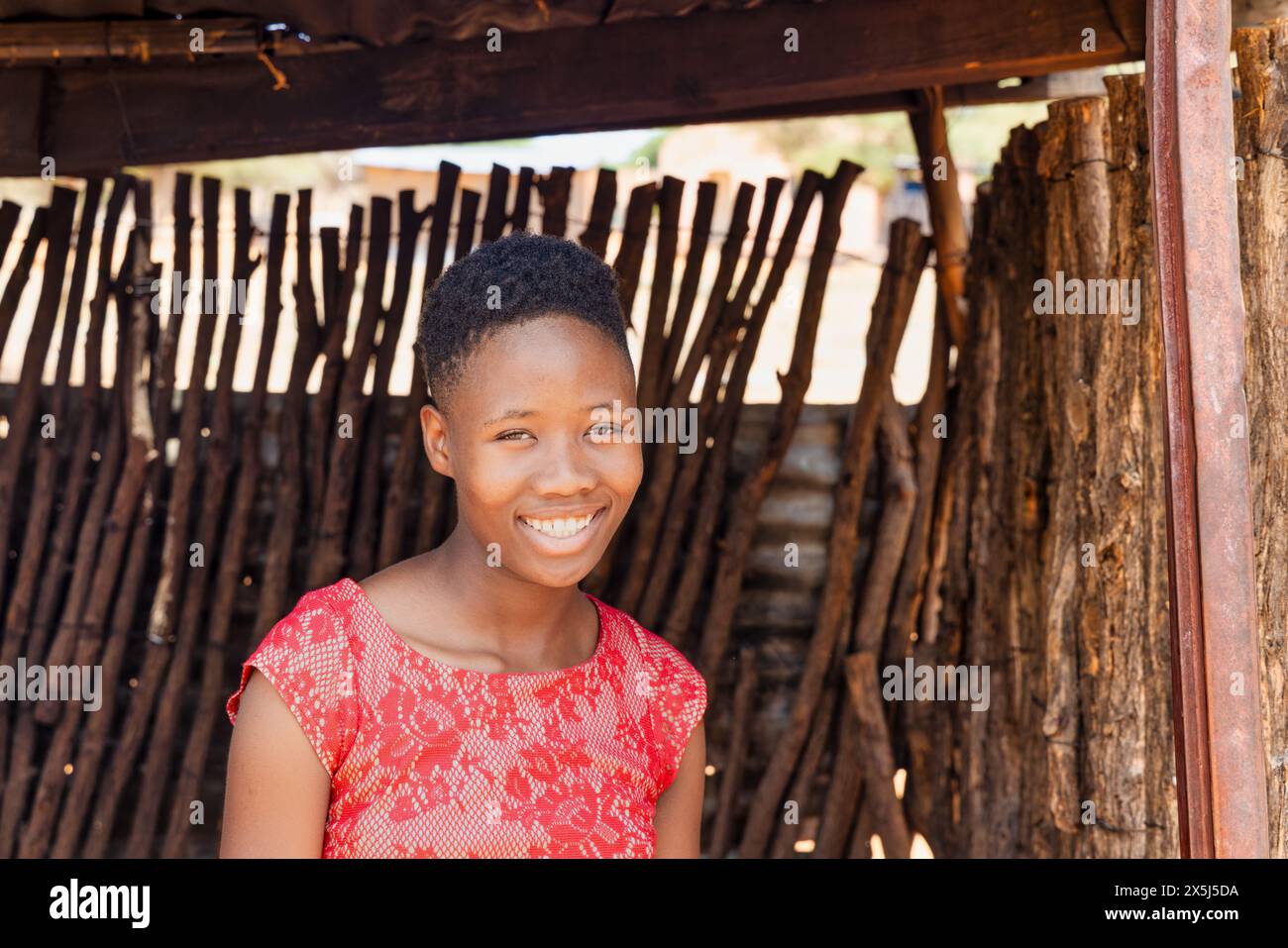 village jeune fille africaine avec robe rouge debout je me tiens debout à l'entrée de la cabane, village de canton en afrique du sud Banque D'Images