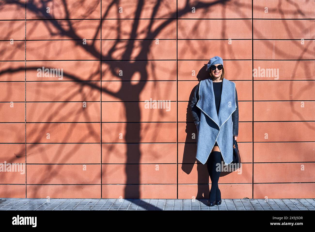 Femme élégante avec ombre dramatique sur le mur orange Banque D'Images