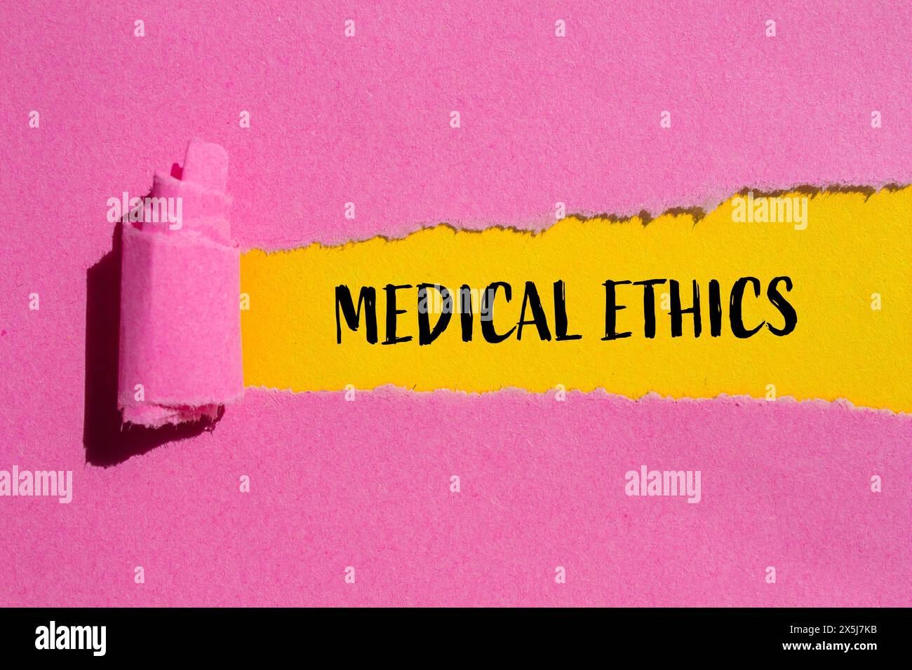 Mots d'éthique médicale écrits sur du papier rose déchiré avec fond jaune. Symbole conceptuel de l'éthique médicale. Copier l'espace. Banque D'Images