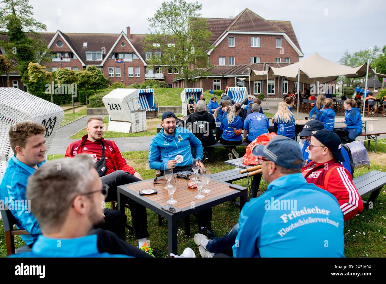 PRODUCTION - 09 mai 2024, basse-Saxe, Neuharlingersiel : de nombreux participants aux Championnats d'Europe de Boßeln et Klootschießen sont assis dans le jardin de l'auberge de jeunesse DJH Resort Neuharlingersiel, qui sert d'hébergement, le 9 mai 2024. Environ 400 athlètes venus d’Allemagne, des pays-Bas, d’Italie, d’Irlande, d’Espagne et de Suisse participeront à la compétition à Neuharlingersiel du 9 au 12 mai. Photo : Hauke-Christian Dittrich/dpa Banque D'Images