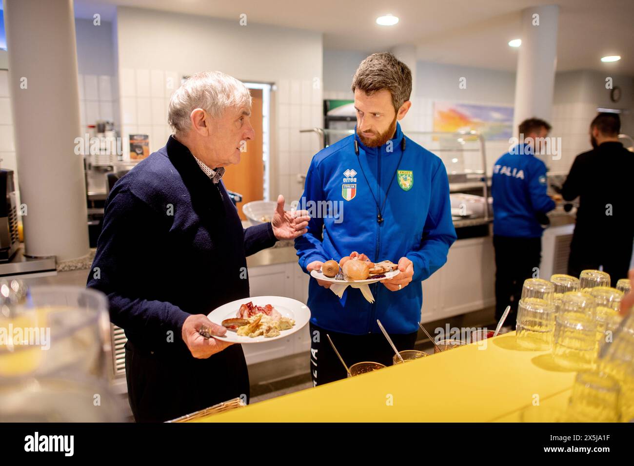 Neuharlingersiel, Allemagne. 10 mai 2024. James O'Driscoll d'Irlande et Riccardo Manieri d'Italie discutent dans la salle de petit déjeuner de l'auberge de jeunesse DJH Resort Neuharlingersiel, qui sert d'hébergement aux participants aux Championnats d'Europe de Boßeln et Klootschießen. Environ 400 athlètes venus d’Allemagne, des pays-Bas, d’Italie, d’Irlande, d’Espagne et de Suisse participeront à la compétition à Neuharlingersiel du 9 au 12 mai. Crédit : Hauke-Christian Dittrich/dpa/Alamy Live News Banque D'Images