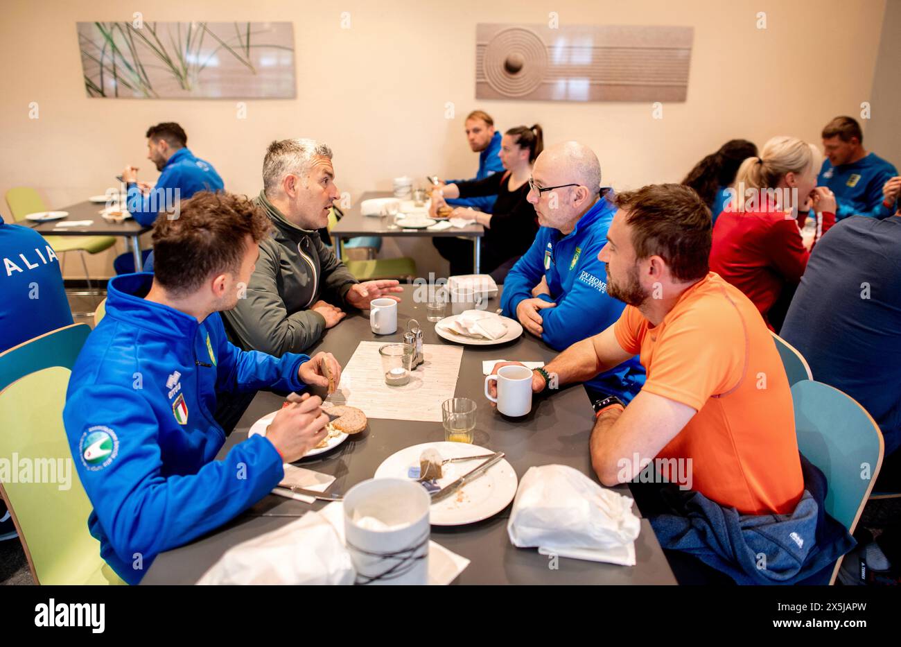 Neuharlingersiel, Allemagne. 10 mai 2024. Les participants italiens sont assis dans la salle de petit déjeuner de l'auberge de jeunesse DJH Resort Neuharlingersiel, qui sert d'hébergement aux participants aux Championnats d'Europe de Boßeln et Klootschießen. Environ 400 athlètes venus d’Allemagne, des pays-Bas, d’Italie, d’Irlande, d’Espagne et de Suisse participeront à la compétition à Neuharlingersiel du 9 au 12 mai. Crédit : Hauke-Christian Dittrich/dpa/Alamy Live News Banque D'Images