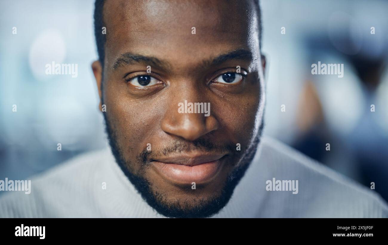 Gros plan Portrait d'un bel homme noir aux yeux brun profond, barbe taillée, à col roulé blanc élégant, clin d'œil et montre un sourire parfait. Attrayant Authentic Gentleman regarde la caméra Banque D'Images