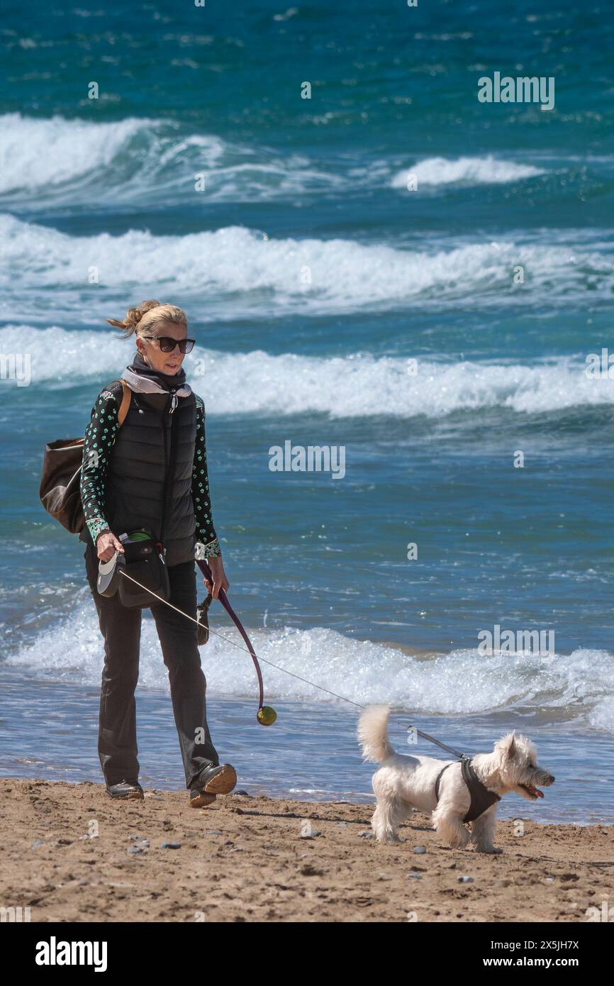 Une femme mûre promenant son chien de compagnie le long de la plage de Fistral Beach, à Newquay en Cornouailles, au Royaume-Uni. Banque D'Images