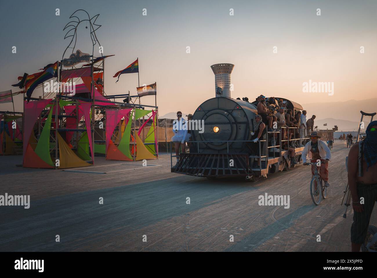 Scène animée du festival de musique et d'art du désert, train vintage et foule éclectique, atmosphère d'aventure Banque D'Images