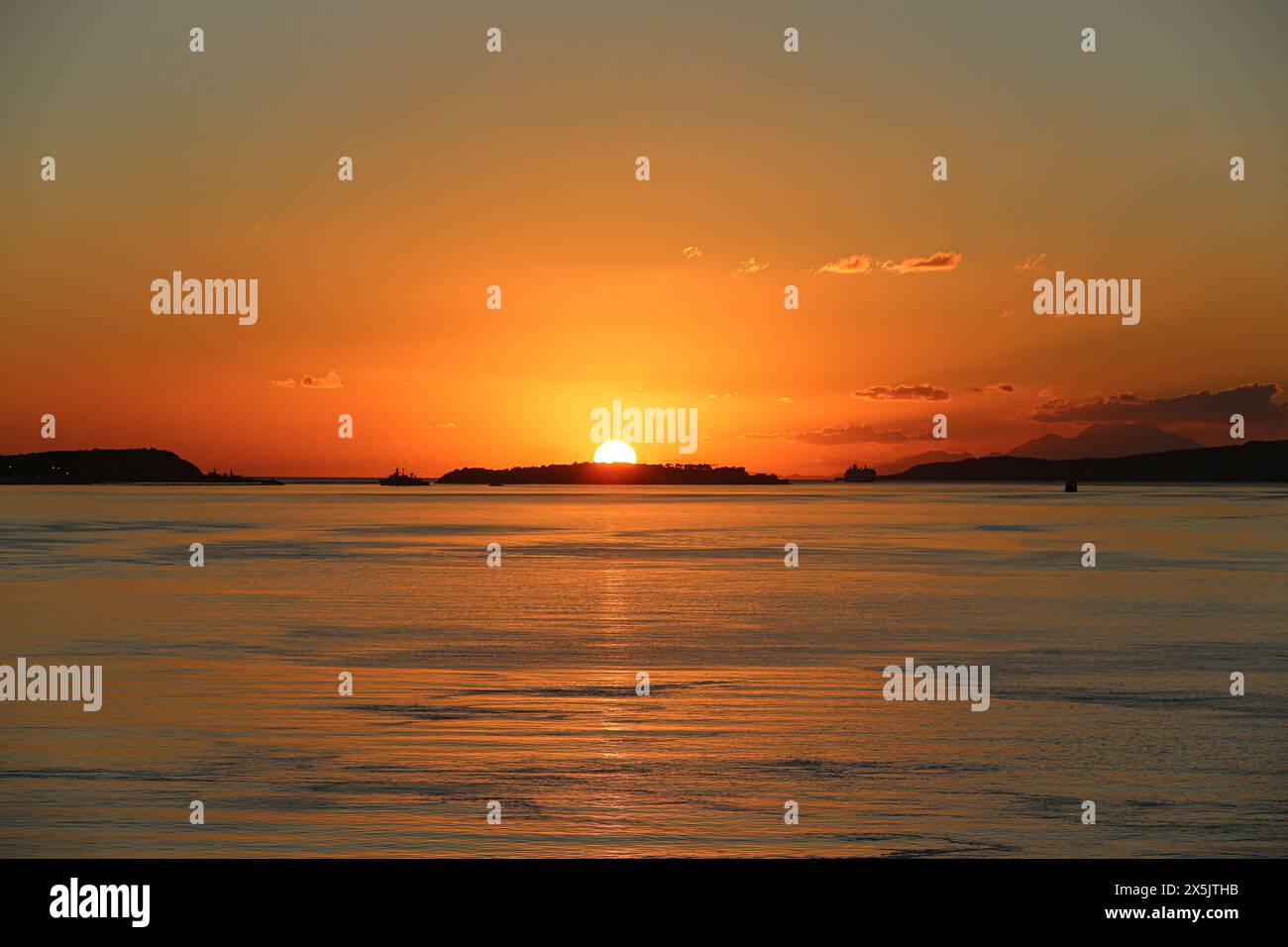 Grèce. Le soleil orange ardent plonge sous l'horizon au-dessus de la mer et des îles Banque D'Images