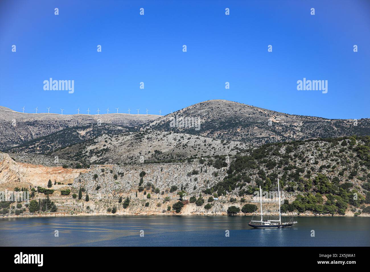 Grèce. Un voilier passe devant une île méditerranéenne grecque avec des éoliennes Banque D'Images