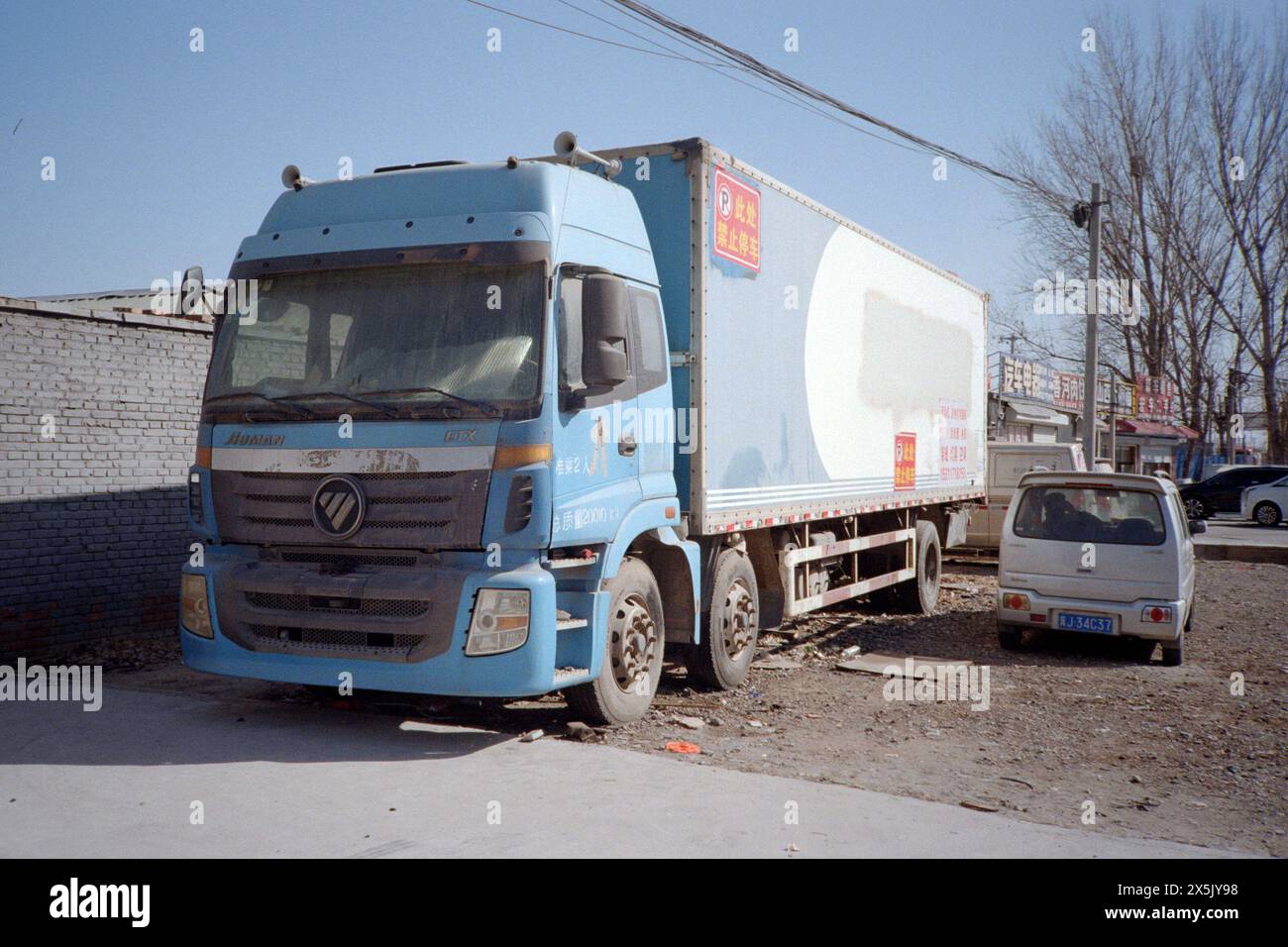 Un vieux camion boîte bleue et une mini voiture au bord de la route à vendre. Banque D'Images