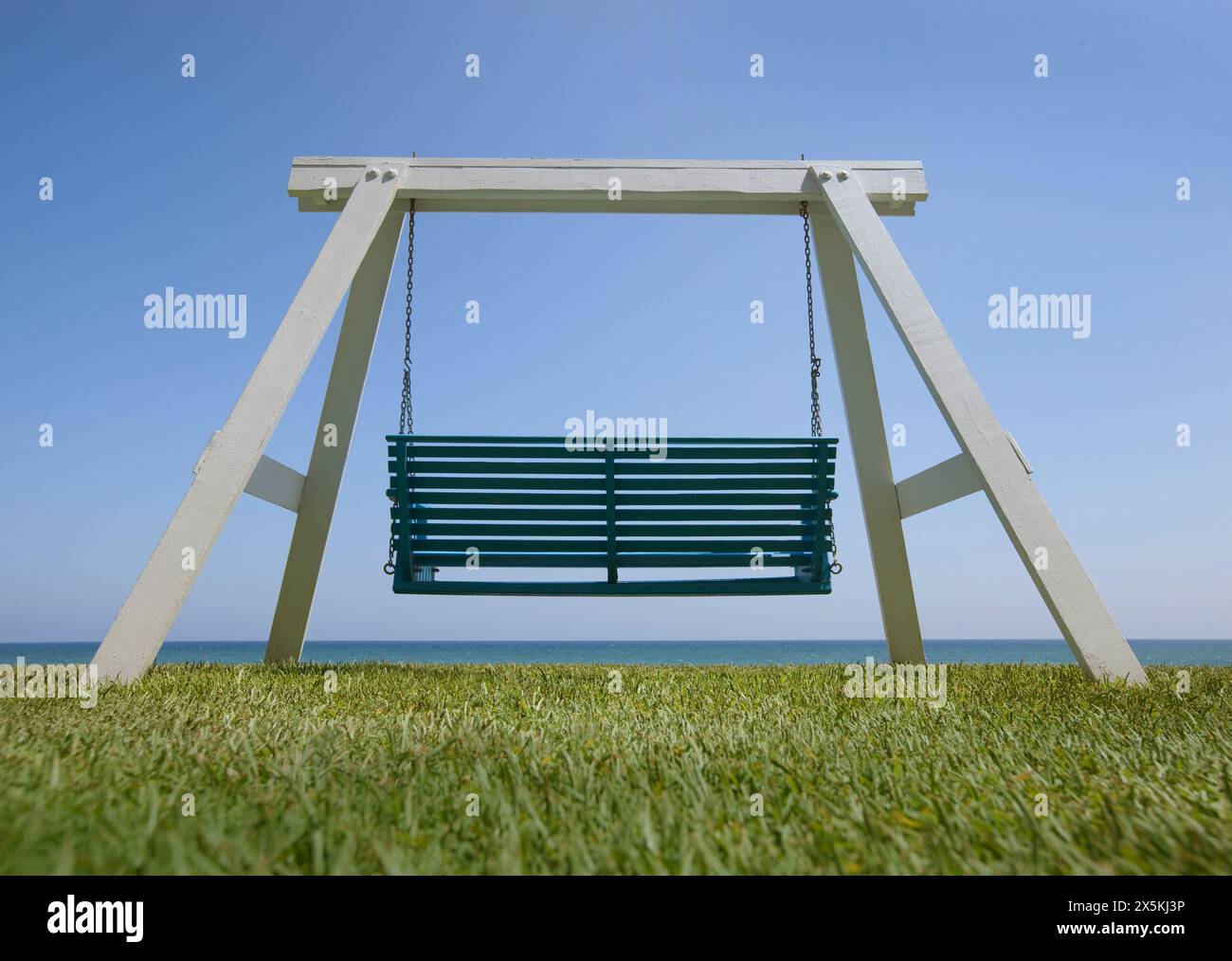 Balançoire de plage en bois avec un siège peint en vert et vue sur la mer. Banque D'Images