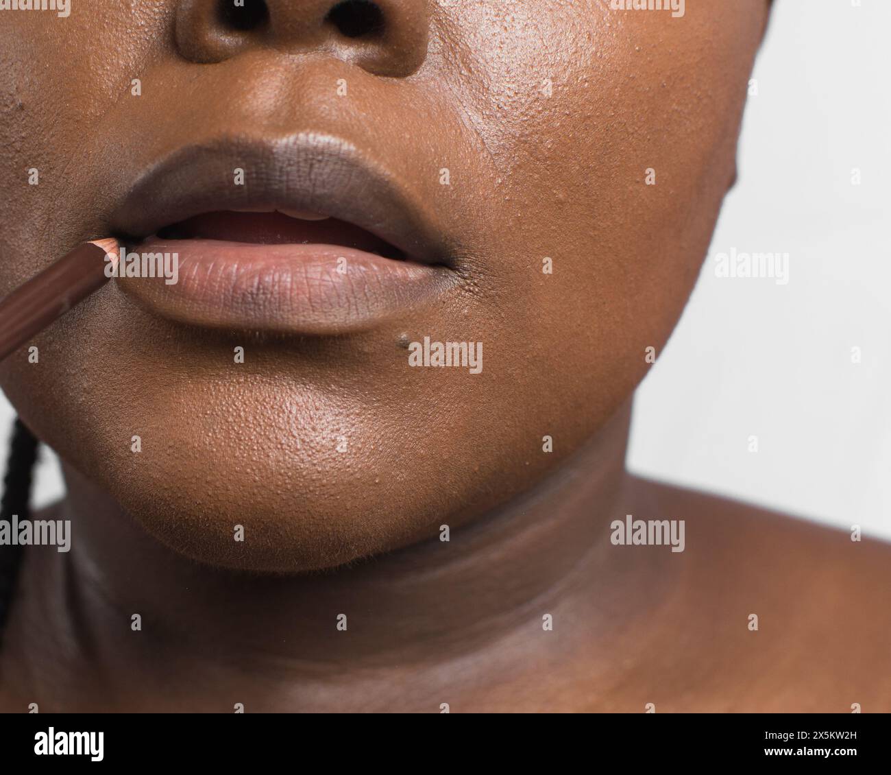 Femme à peau brune appliquant un crayon à lèvres brun, femme à peau foncée utilisant un produit à lèvres, portrait d'application de maquillage Banque D'Images