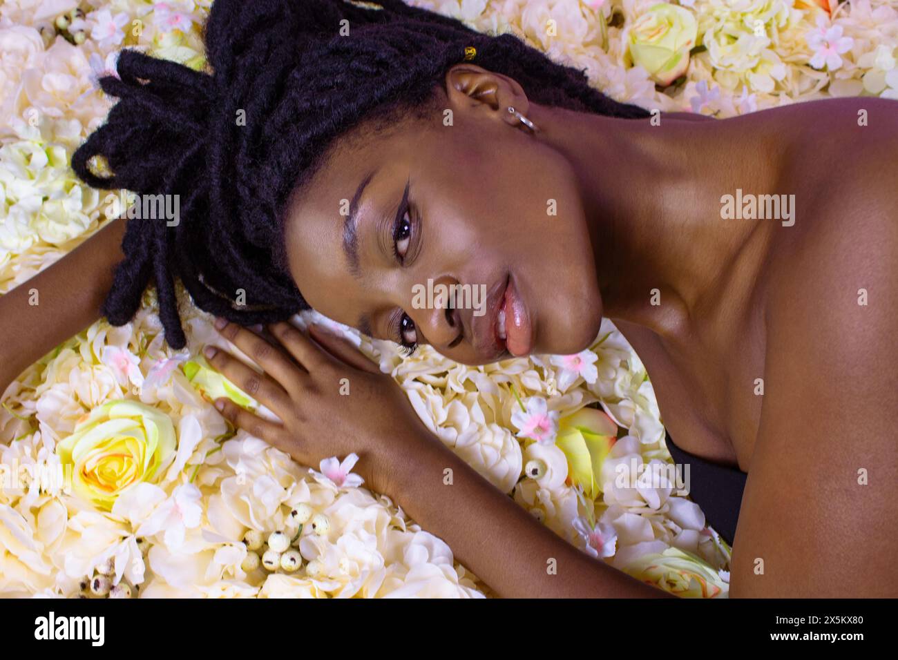 Portrait studio d'une jeune femme couchée sur des fleurs Banque D'Images