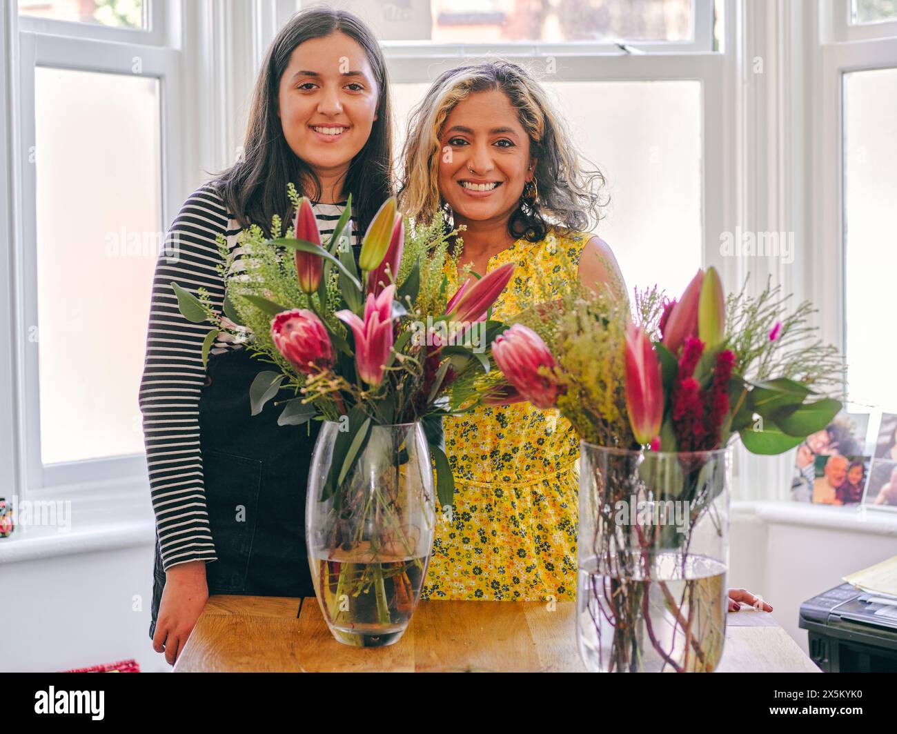 Des femmes souriantes debout à côté de bouquets dans des vases Banque D'Images