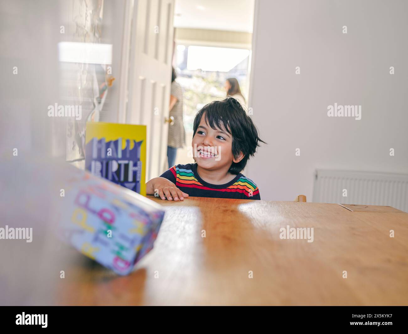 Garçon souriant assis à table avec des cadeaux d'anniversaire Banque D'Images