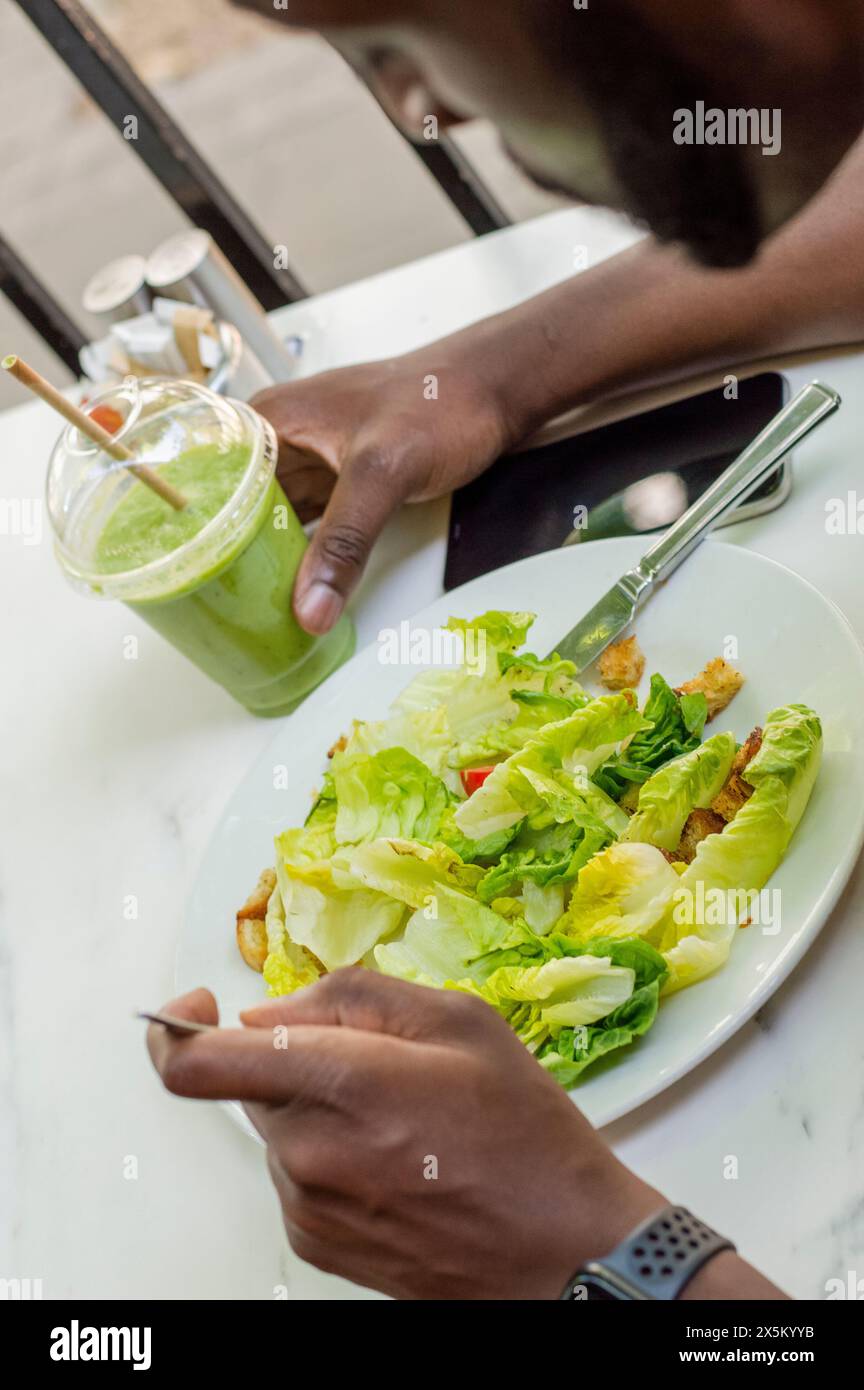Homme adulte moyen mangeant de la salade Banque D'Images