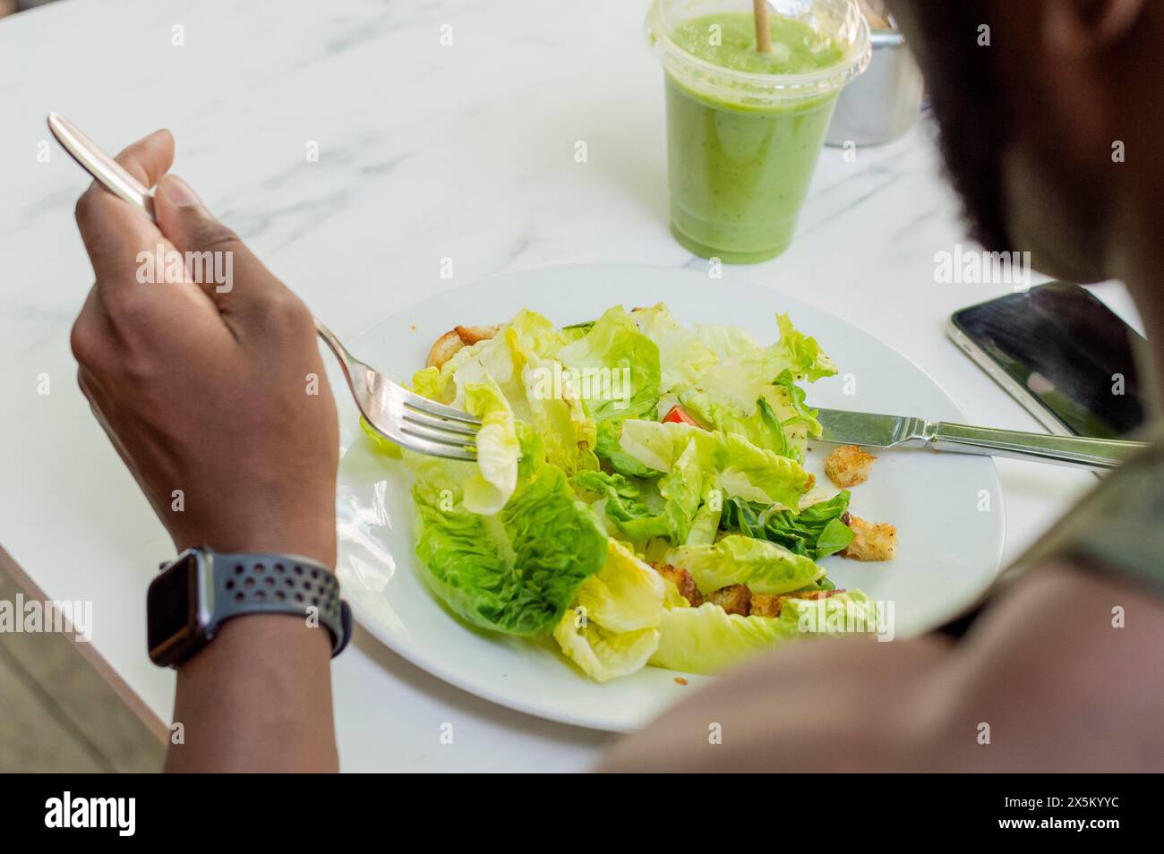 Homme adulte moyen mangeant de la salade Banque D'Images