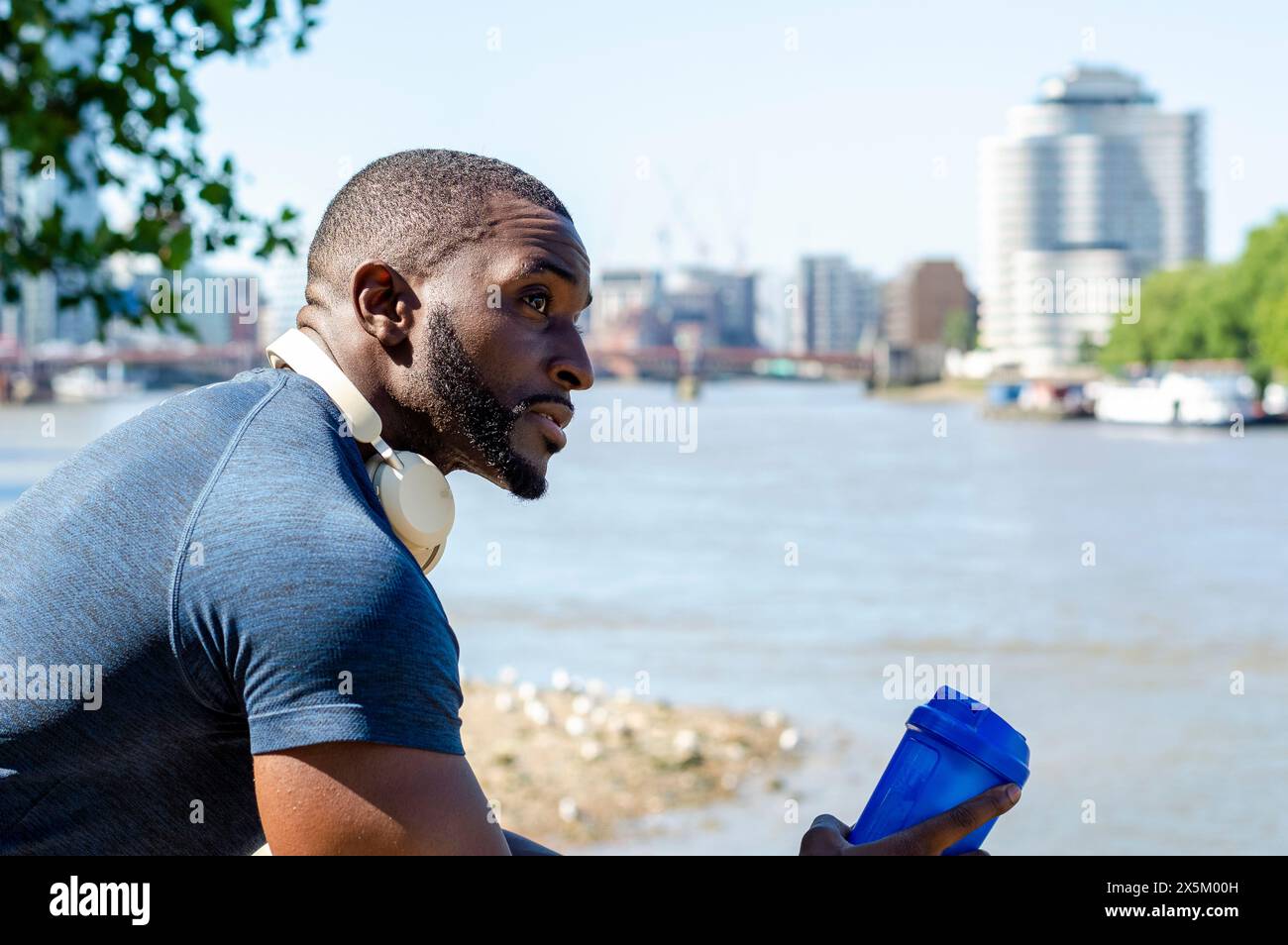 Homme tenant un récipient d'eau en plastique et regardant la rivière de la ville Banque D'Images