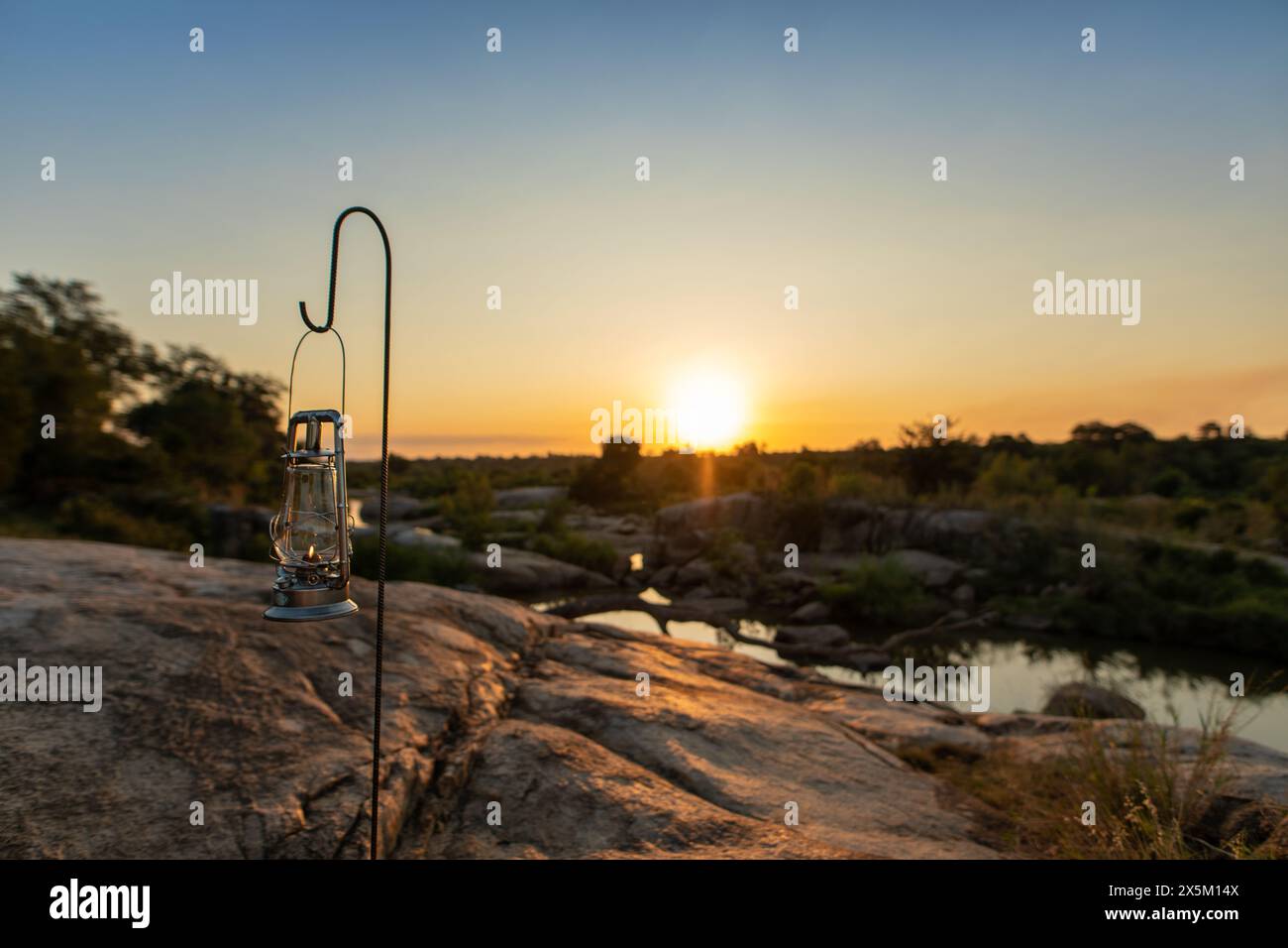 Une lanterne placée à côté d'une rivière pendant le coucher du soleil. Banque D'Images