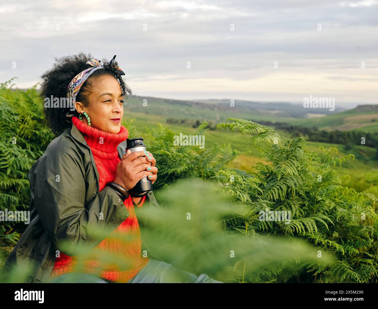 Femme tenant un récipient de boisson isolé et regardant le paysage Banque D'Images