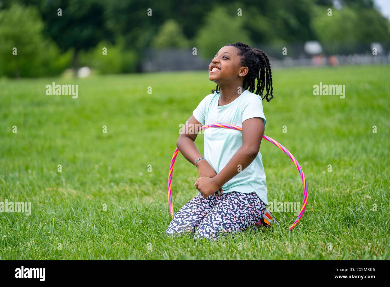 Fille utilisant le cerceau en plastique dans le parc Banque D'Images