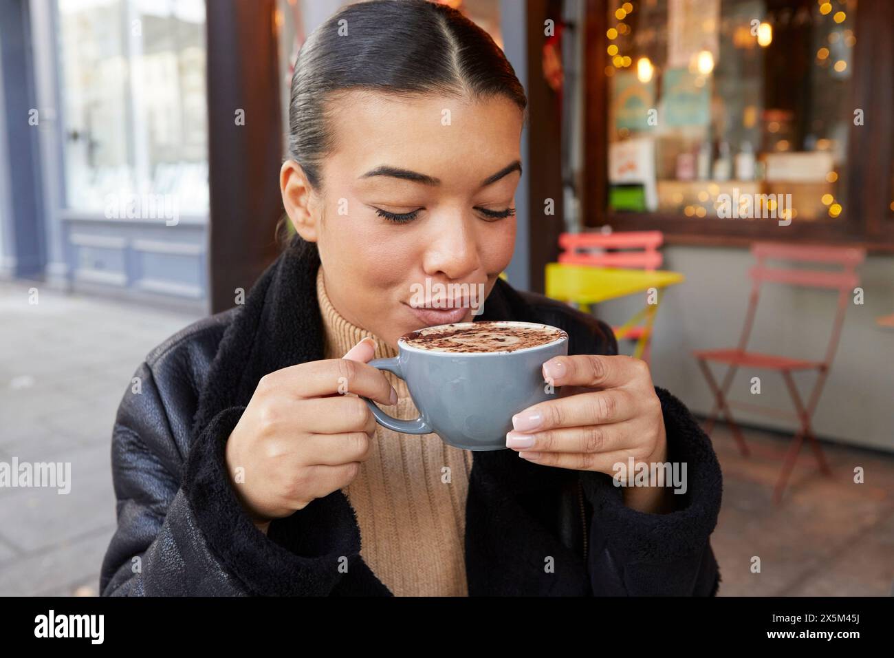 Femme adulte moyenne buvant du café dans le café trottoir Banque D'Images