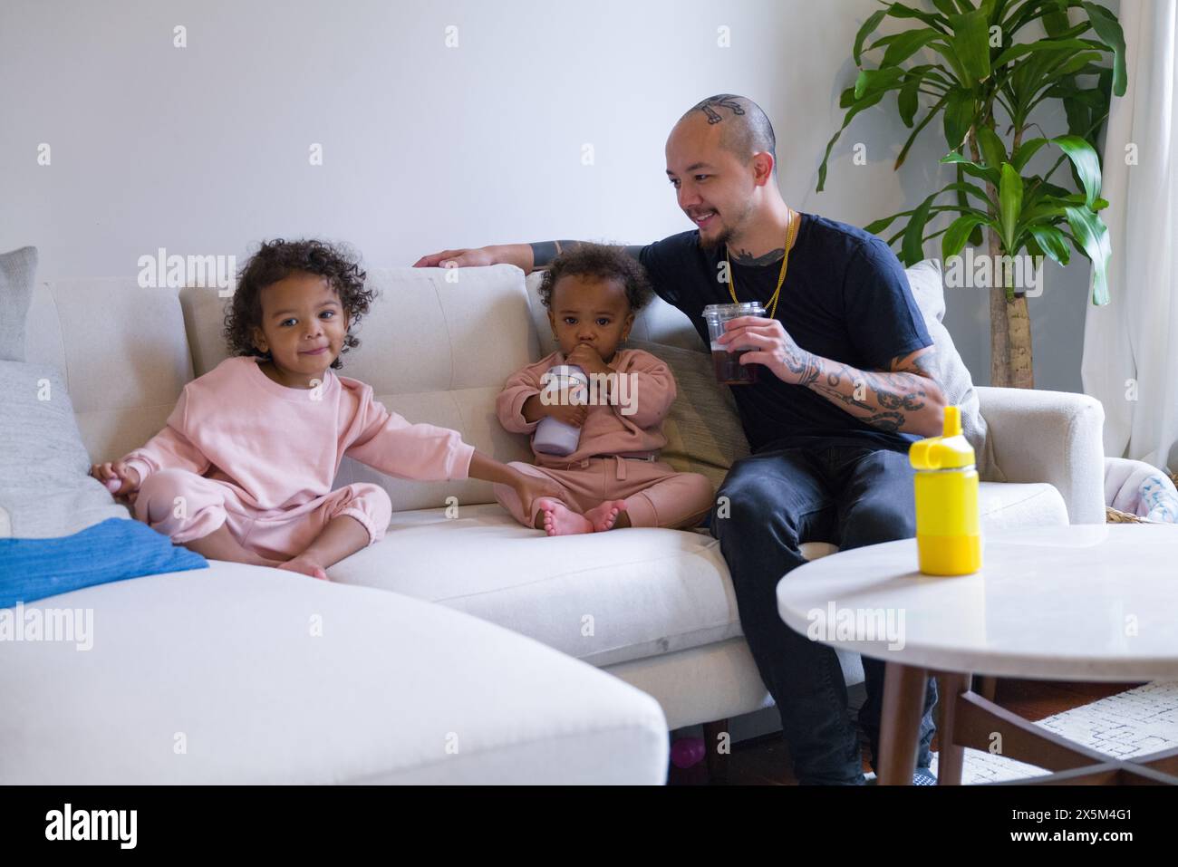 Père et filles assis sur le canapé Banque D'Images