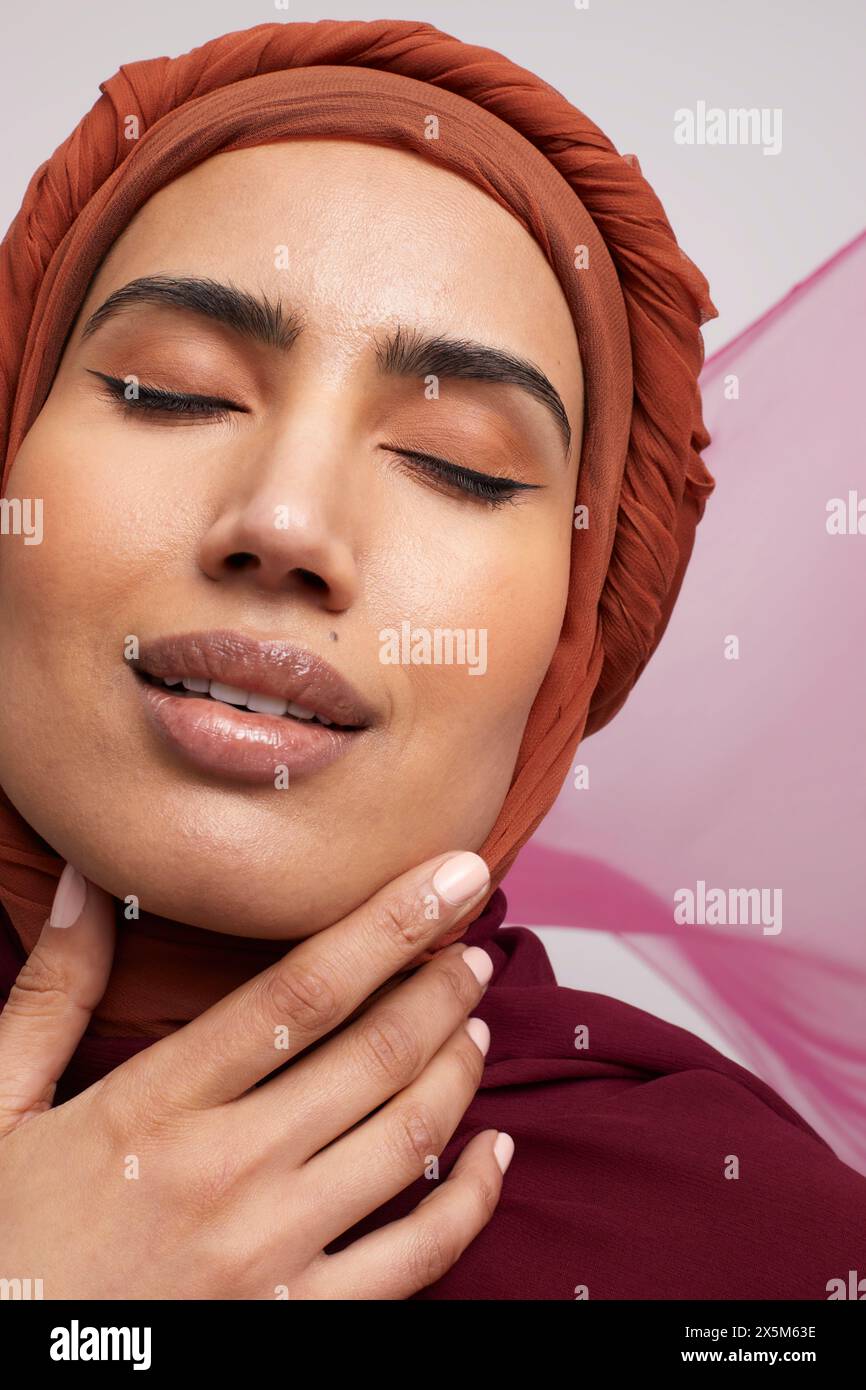 Portrait de studio d'une femme portant du brownhijab avec les yeux fermés Banque D'Images
