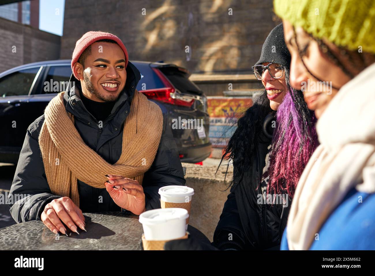 USA, New York City, amis souriants appréciant le café à table dans la ville Banque D'Images