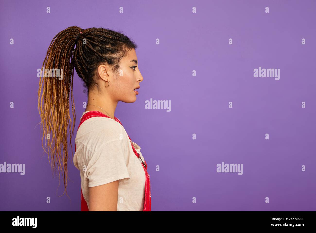 Profil de femme avec des cheveux tressés sur fond violet Banque D'Images